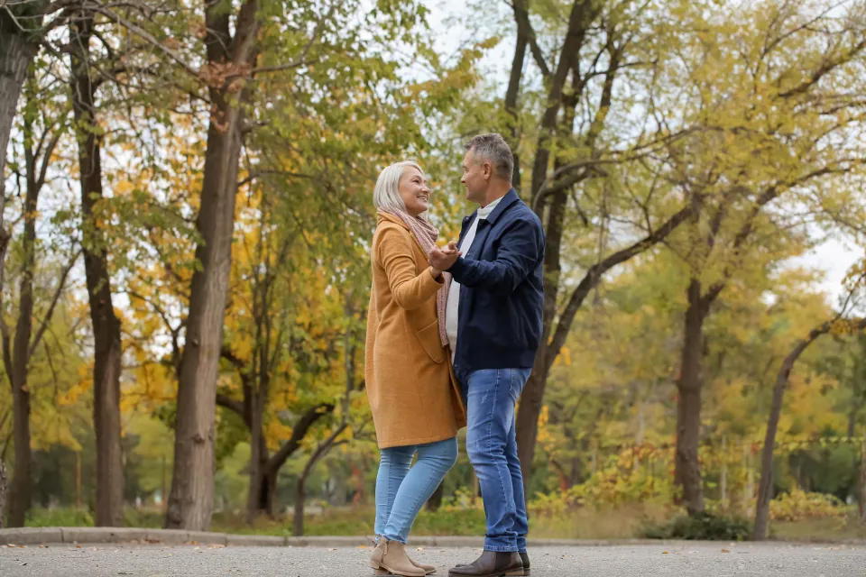 An older couple dancing in a park in autumn