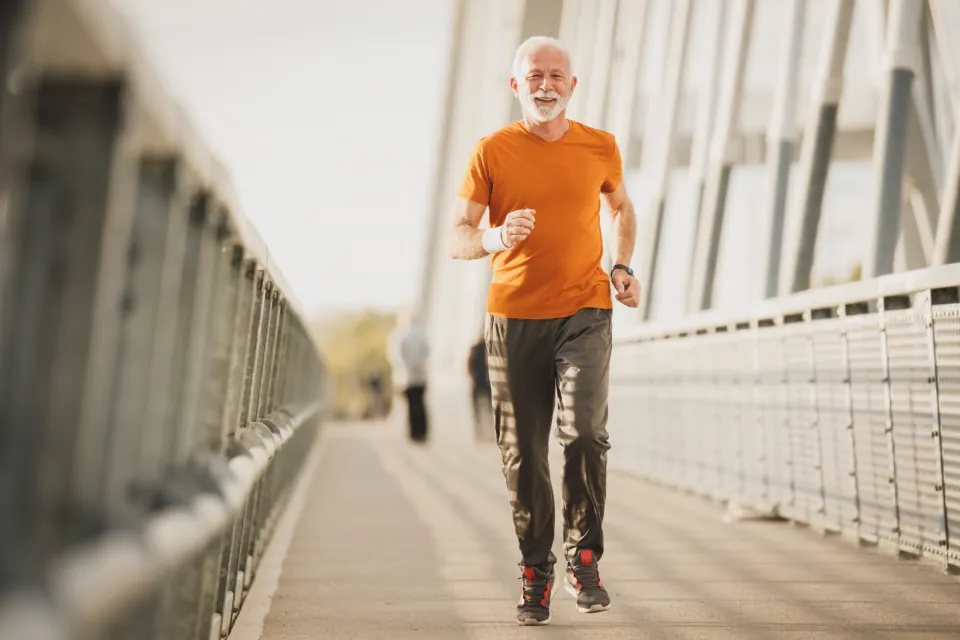 An older man jogging across a footbridge